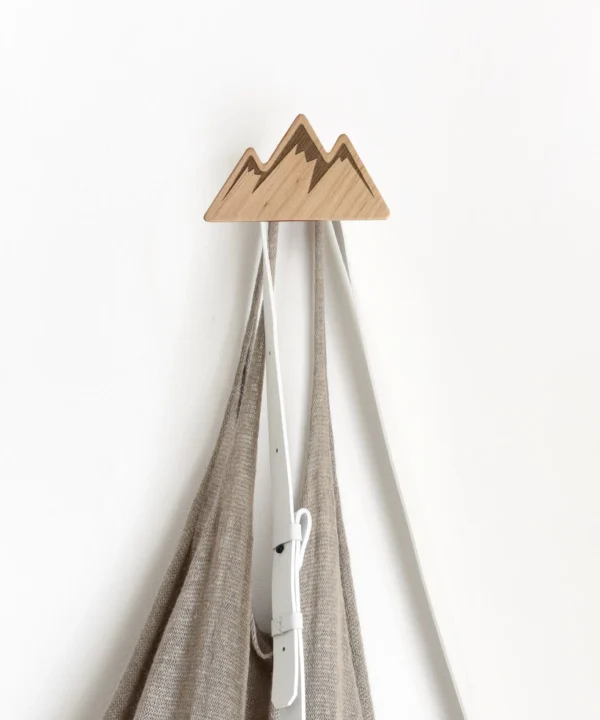 Kalno formos drabužių kabliukas laikantis pilką maišelį ir baltą diržą.