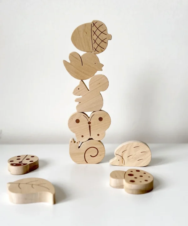 Vertikaliai subalansuotas medinių miško figūrėlių bokštas, lavinantis vaiko kantrybę ir motoriką.