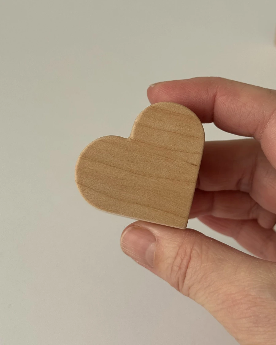 Rankoje laikoma medinė širdelė, parodanti realų produkto dydį ir natūralaus medžio faktūrą.