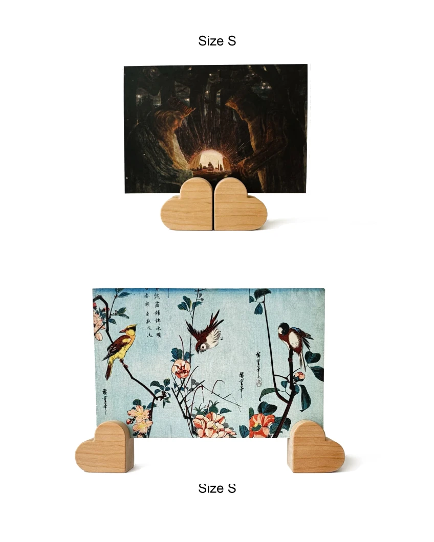 Didelis atvirukas su paukščiais, stabiliai laikomas dviejų medinių širdelės formos laikiklių.