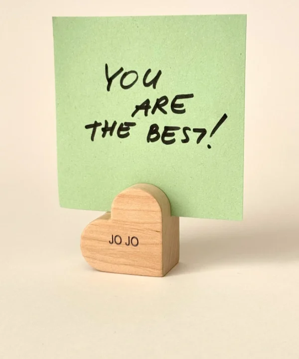 Graviruotas medinis širdelės laikiklis su vardu JO JO, laikantis žalią lapelį su užrašu You are the best.